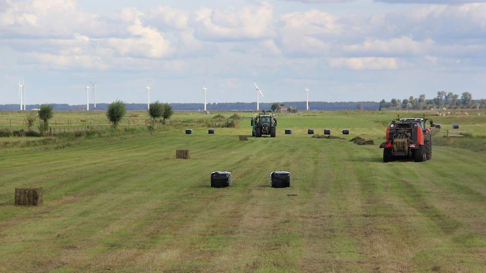 Bert Post, eigenaar van het loonwerkbedrijf aan de Meentweg in Eemnes heeft de grote balenpers zojuist afgekoppeld en gaat verder met de kleinere rode Kuhn die balen maakt van 80x70 centimeter.